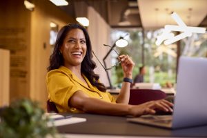 femme qui sourit, assise sur un bureau